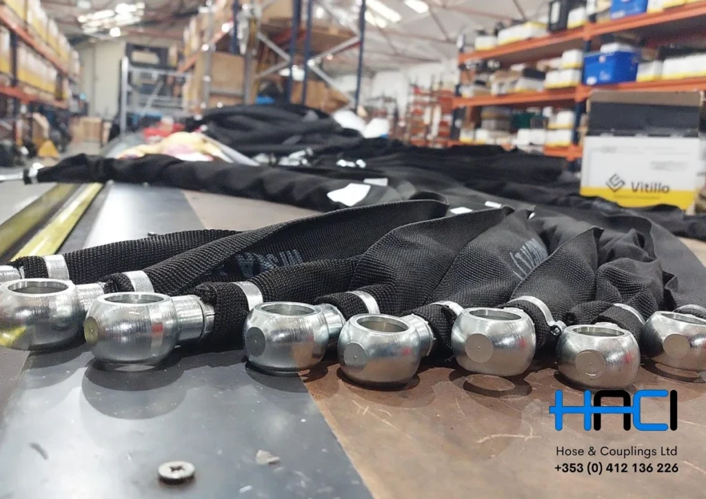 Hydraulic hose assemblies with metal fittings and black protective sleeves at HACI.