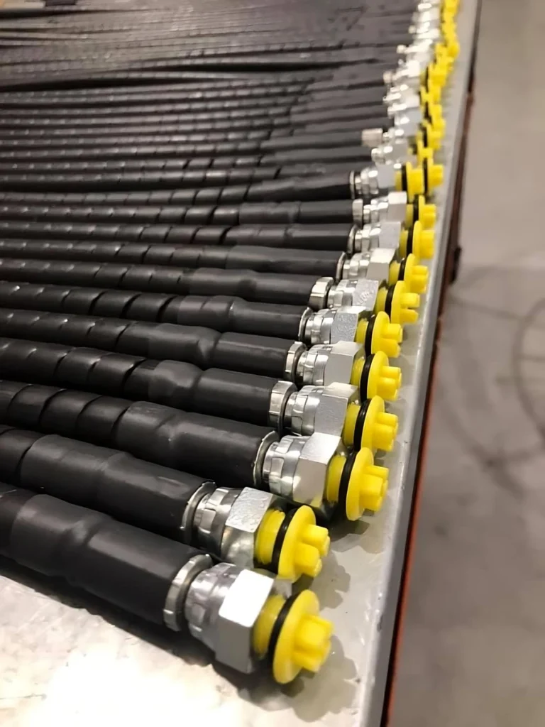 Rows of replacement hydraulic hose assemblies with spiral protection and yellow-capped fittings.